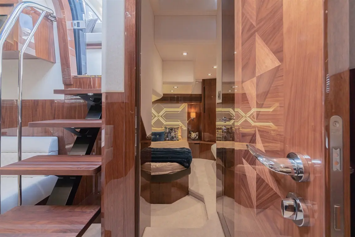 Luxury yacht interior featuring wooden stairs, a stylish door, and a glimpse of a tastefully decorated cabin area.